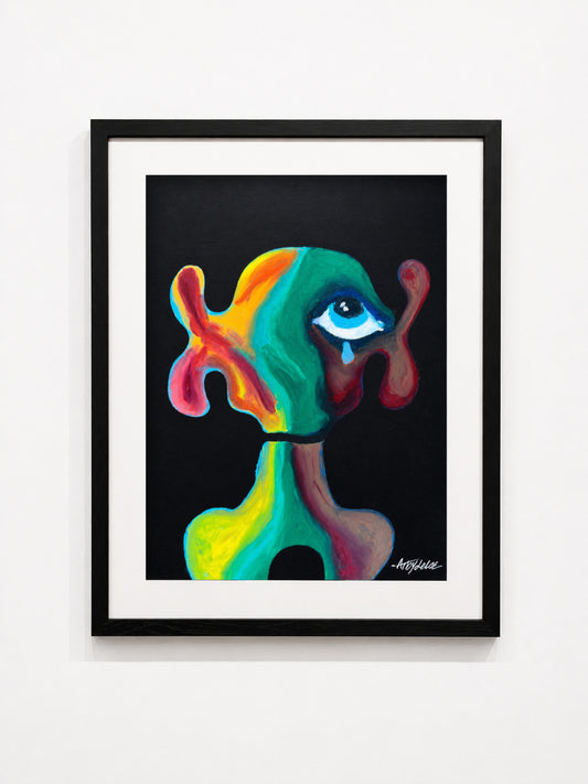 A framed abstract art print featuring a colorful, surreal figure with a single eye on a black background, presented in a black frame with a white mat against a white wall.